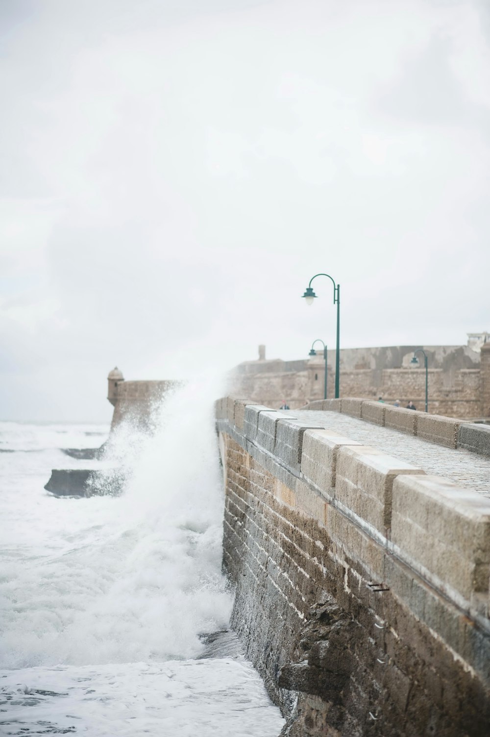 una persona in piedi sul bordo di un muro vicino all'oceano