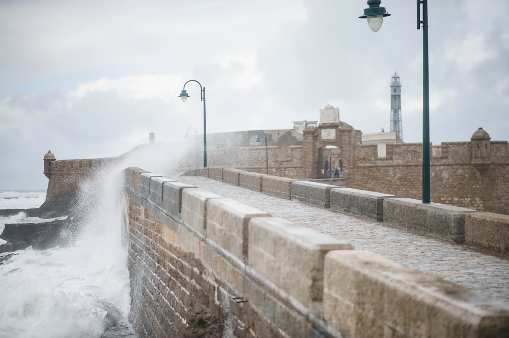 a large wave crashing against a stone wall