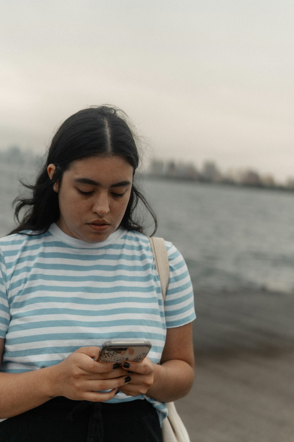 a woman standing on a beach looking at her cell phone