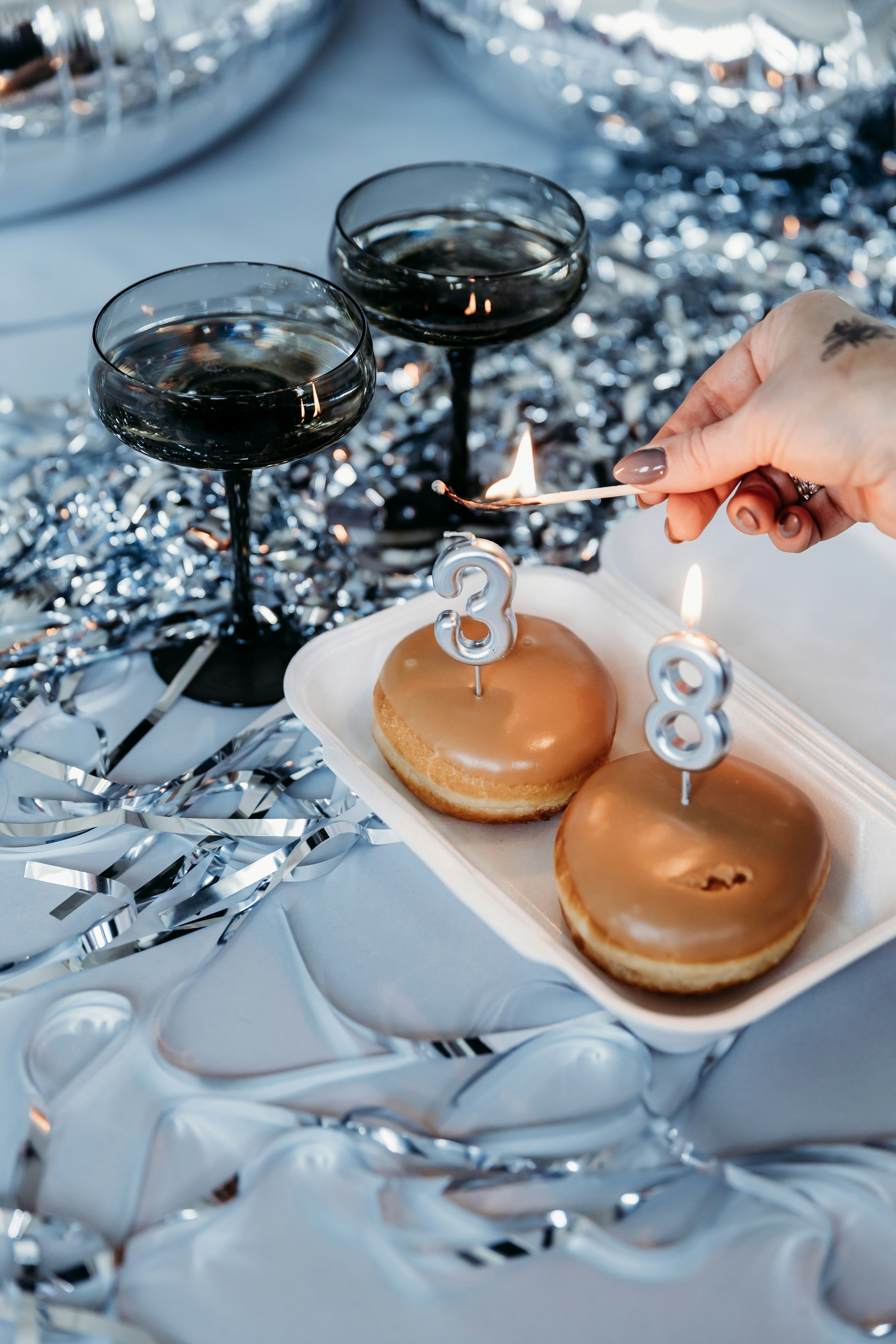 a person lighting a candle on some donuts