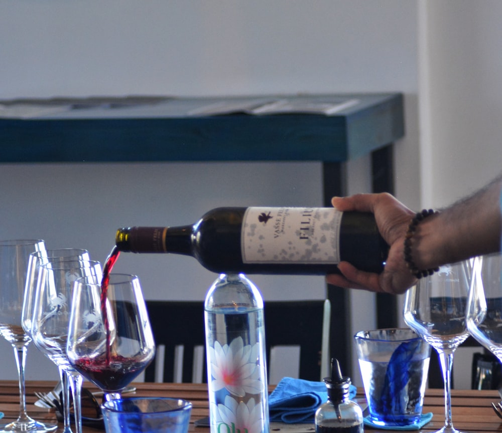 a person pouring wine into a wine glass