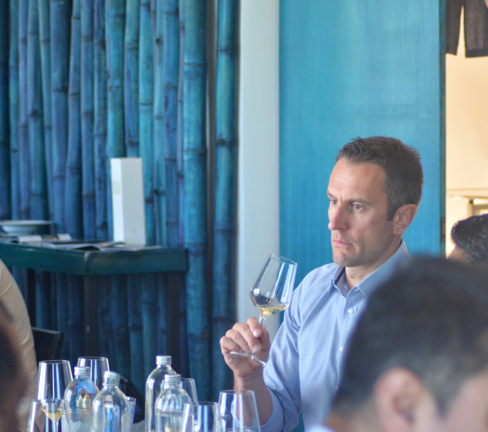 a man sitting at a table with a glass of wine