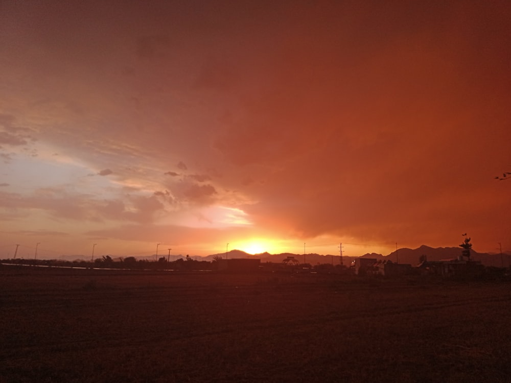 the sun is setting over a field of grass