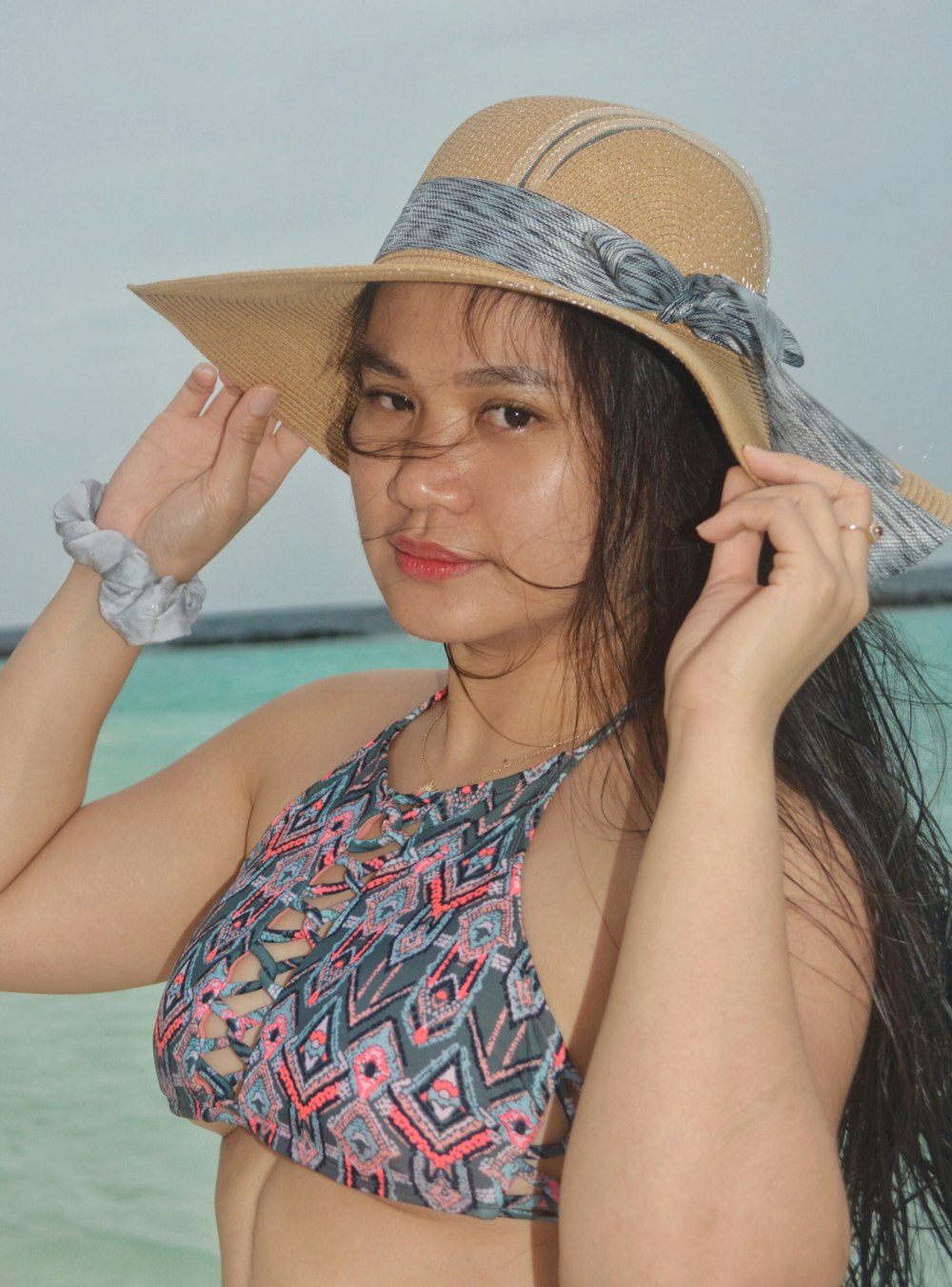 a woman in a bikini and a hat on the beach