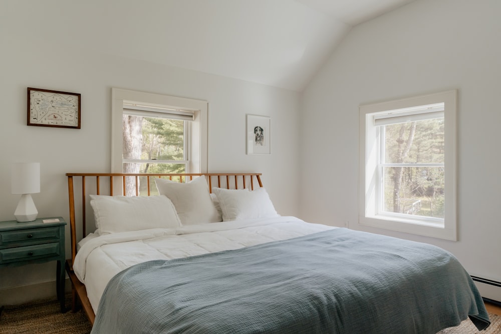 a bed sitting in a bedroom next to two windows