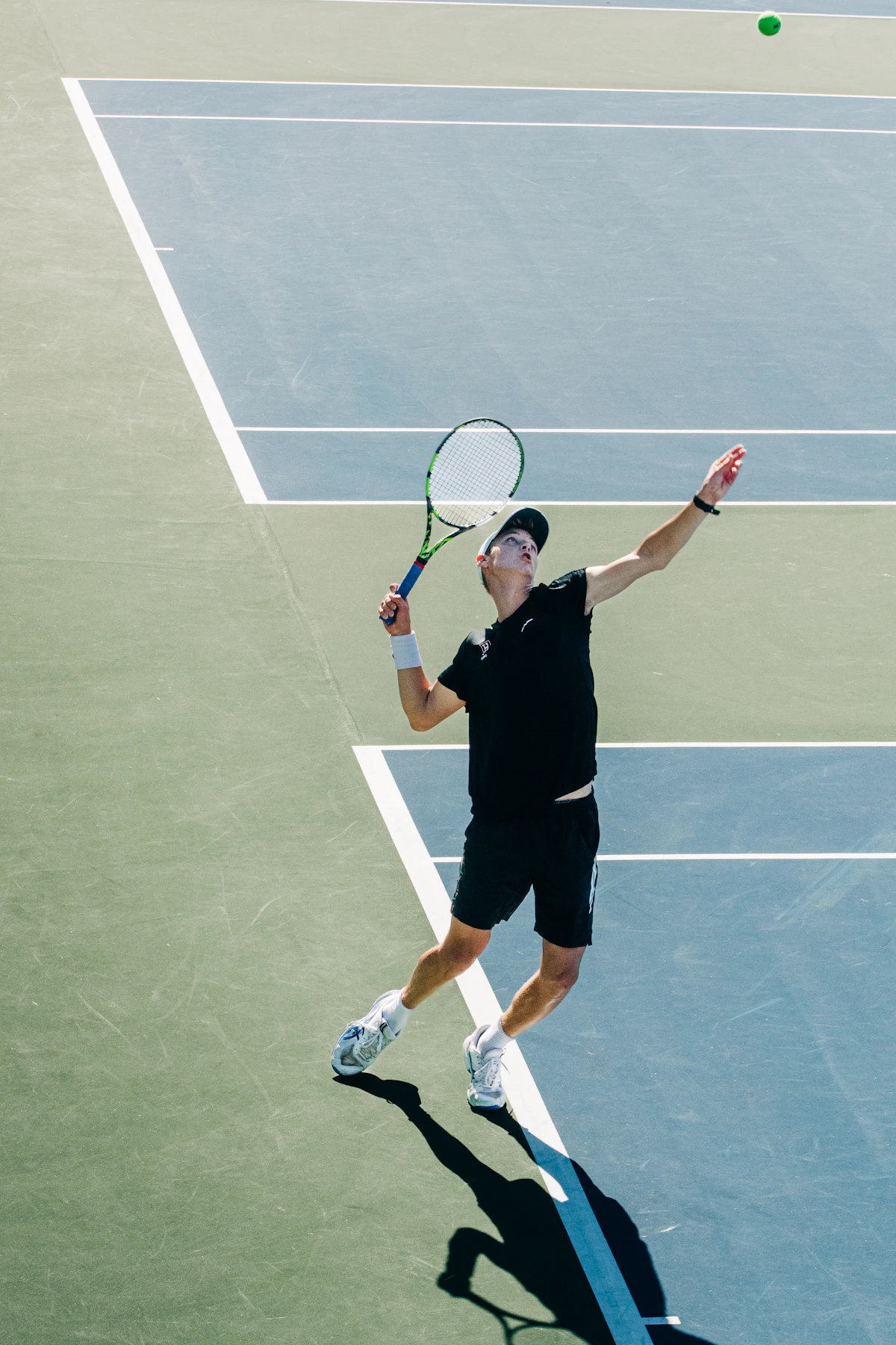 Jugador de tenis saltando en el saque, visto desde arriba sobre una pista rápida