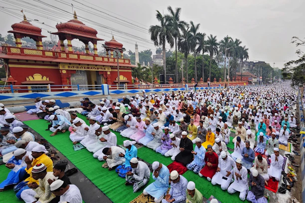 a large group of people sitting on top of a green field