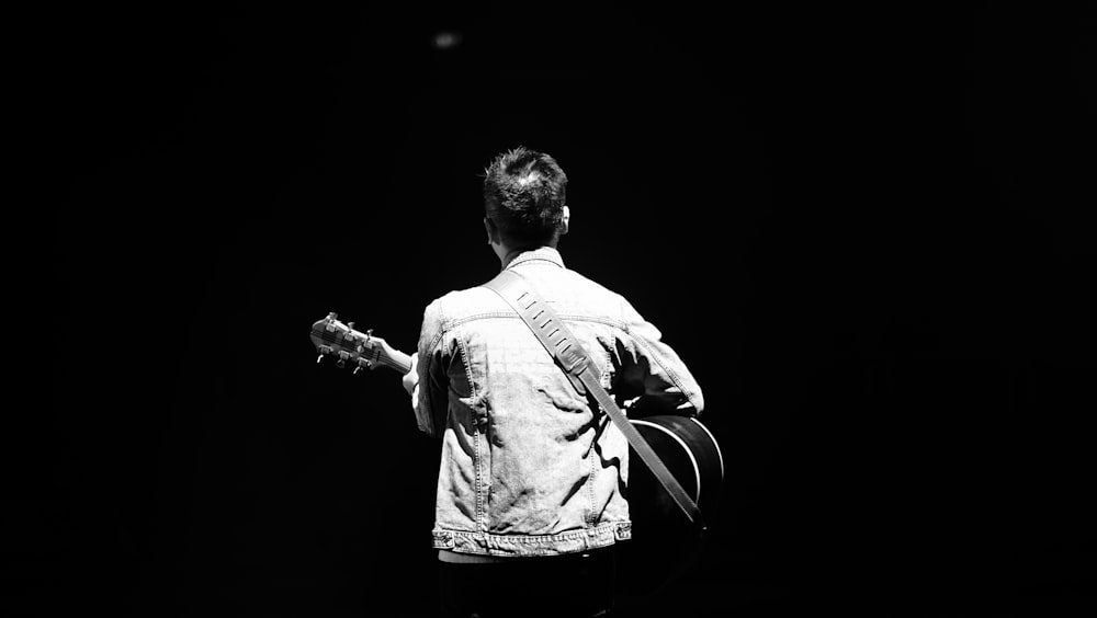 a black and white photo of a man with a guitar