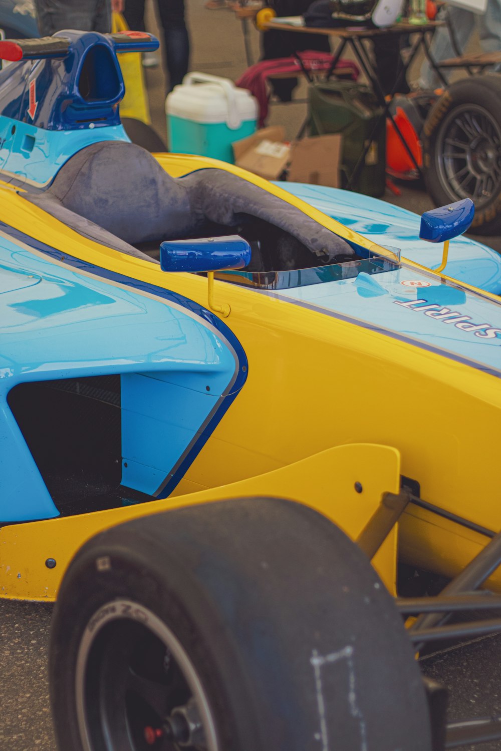 a blue and yellow race car parked on the side of the road