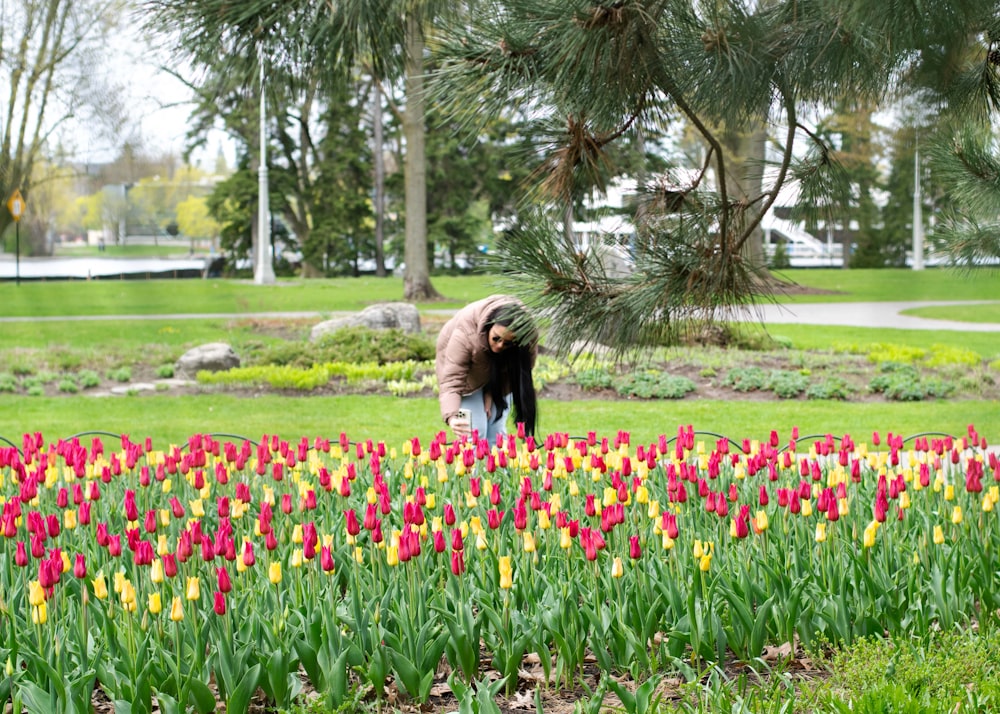 a woman kneeling down in a field of flowers