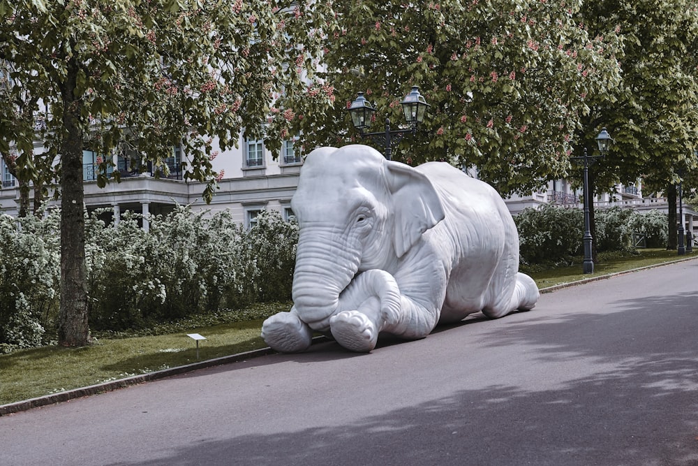 un gran elefante blanco tendido al costado de una carretera