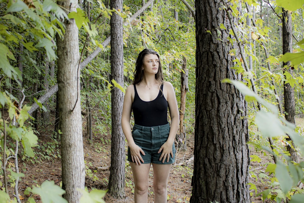 a woman standing in the middle of a forest