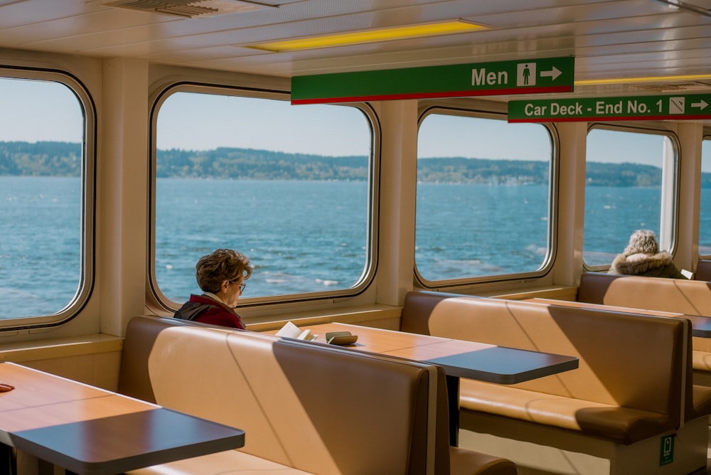 a woman sitting at a table looking out the window of a boat