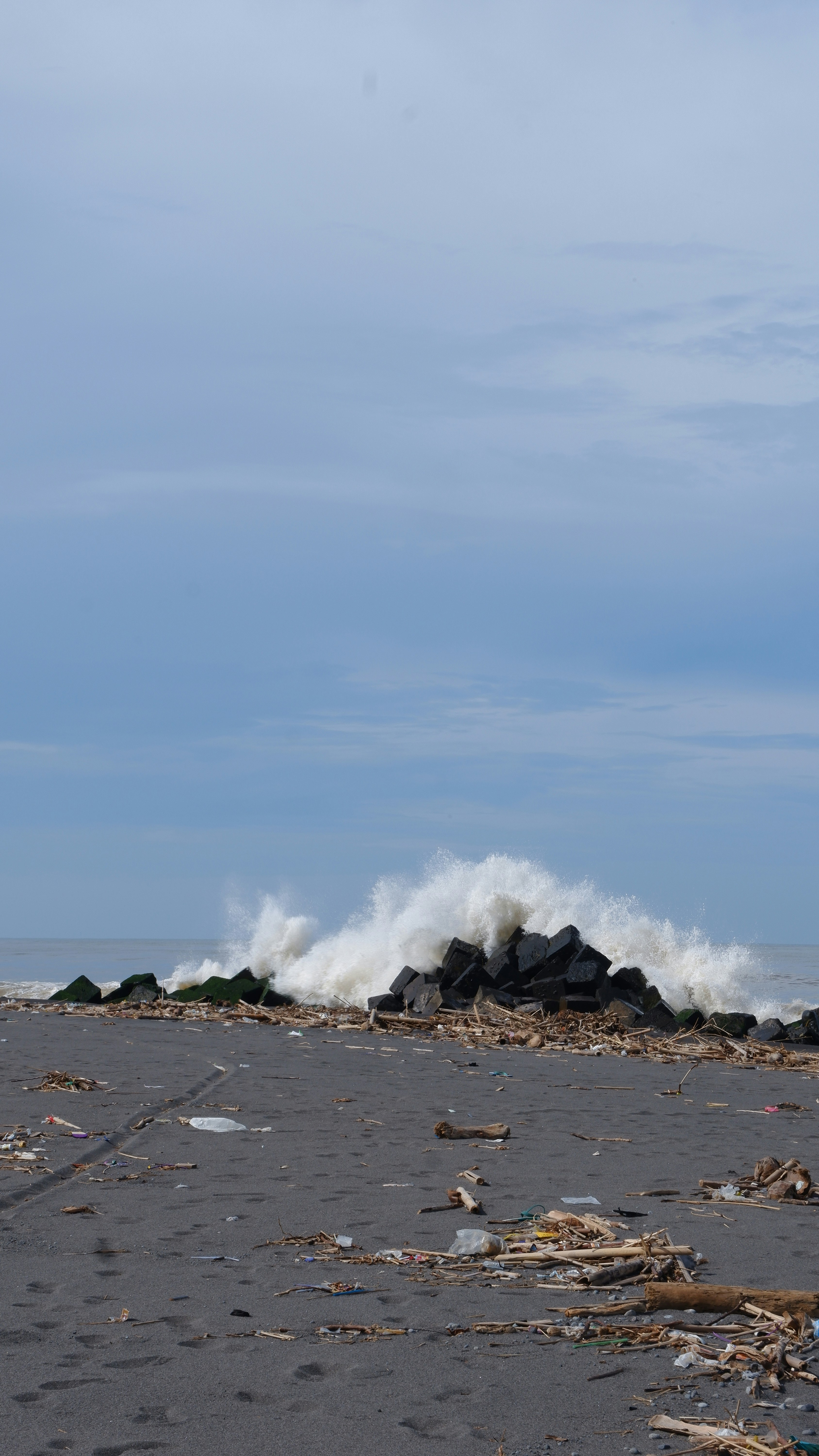 pantai dengan sekelompok puing-puing dan ombak yang menghantamnya