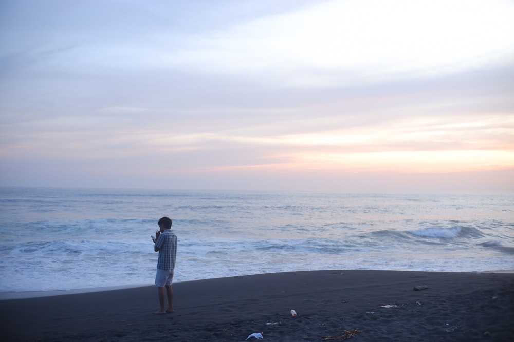 a man standing on a beach next to the ocean