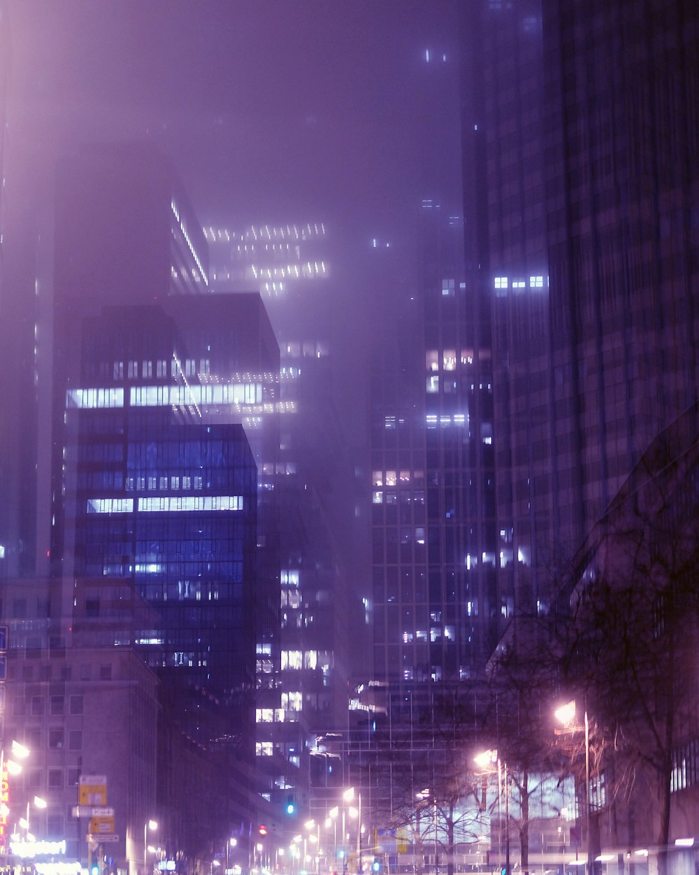 a city street at night with tall buildings