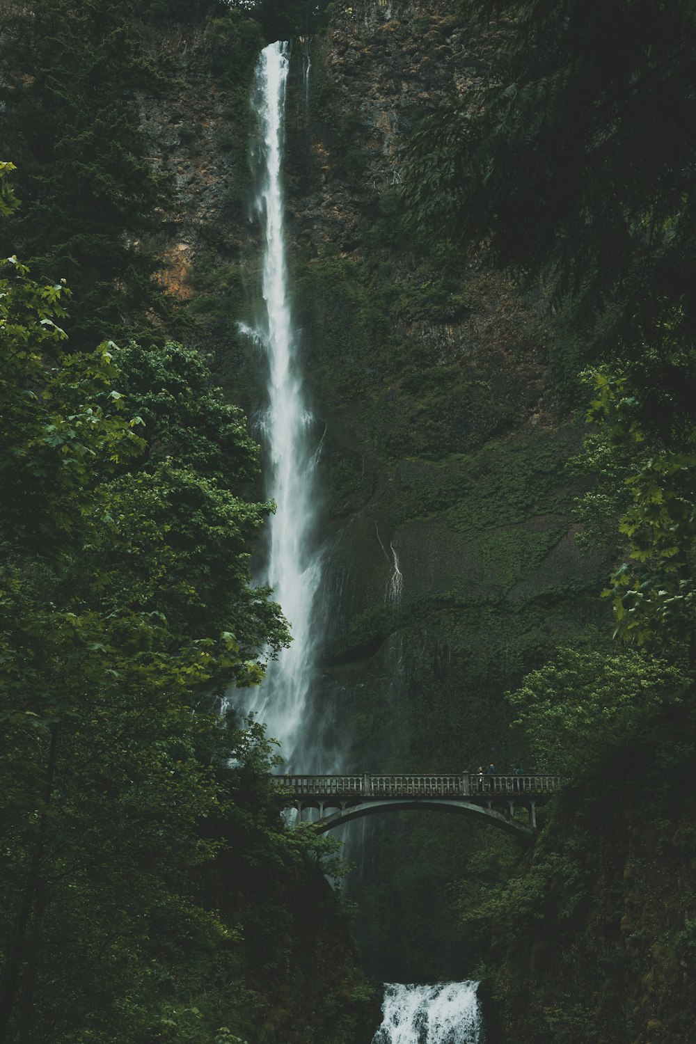 a waterfall with a bridge in the middle of it