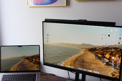 a laptop computer sitting on top of a desk next to a monitor