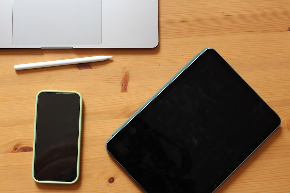 Laptop, Handy und Stift auf einem Holztisch