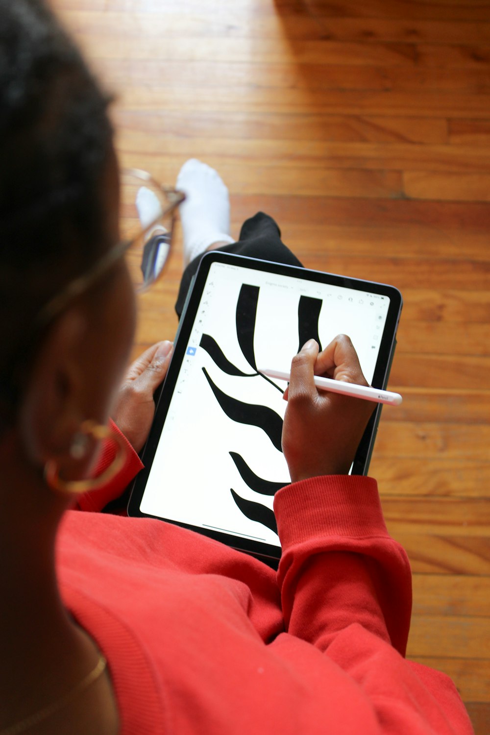 a person sitting on the floor drawing on a tablet