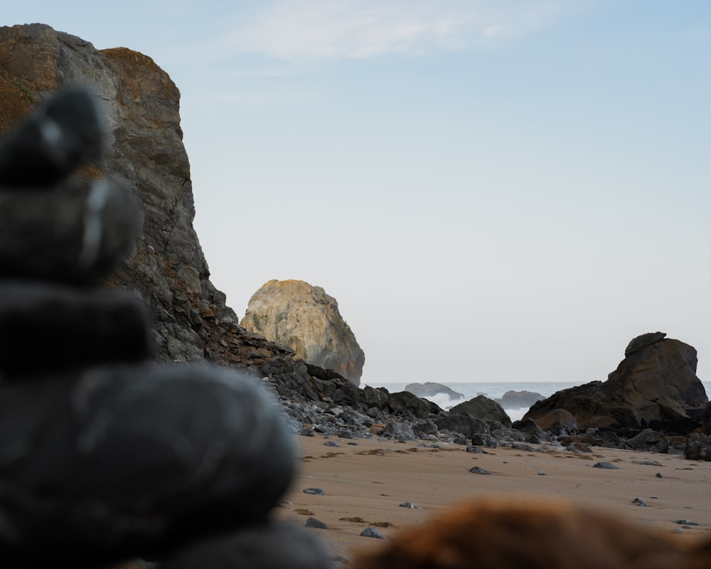 a rock formation on a beach with a large rock in the background