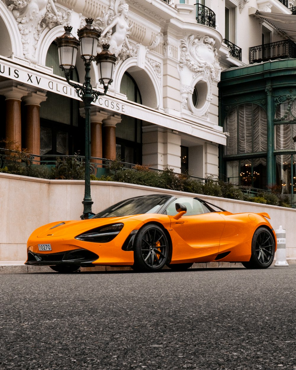 an orange sports car parked in front of a building