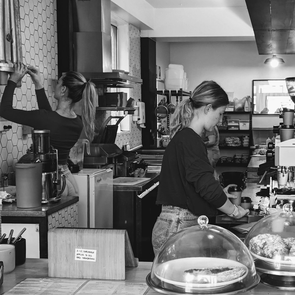 a couple of women standing in a kitchen preparing food