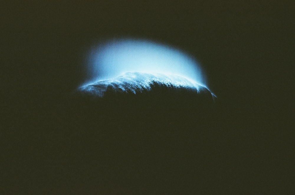 a large wave in the dark with a bright blue light