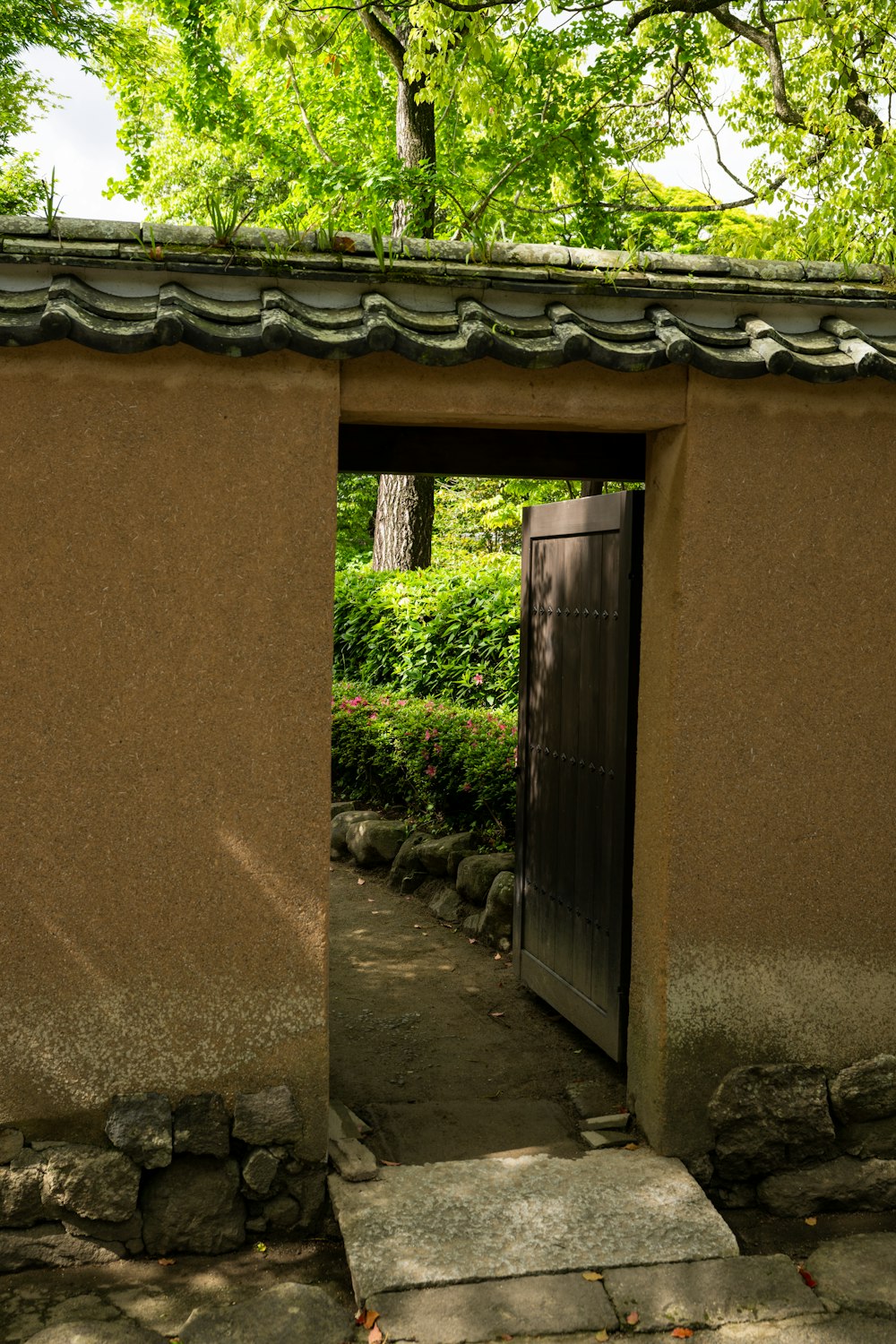 an open door in a stone wall with a tree in the background