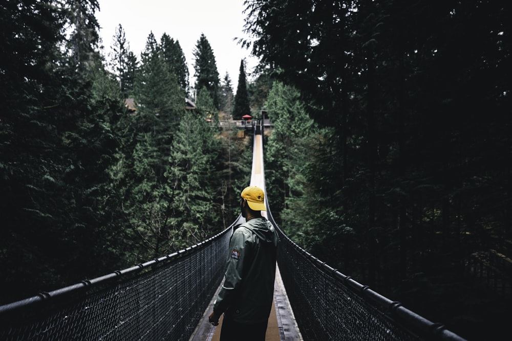 a man standing on a suspension bridge over a forest