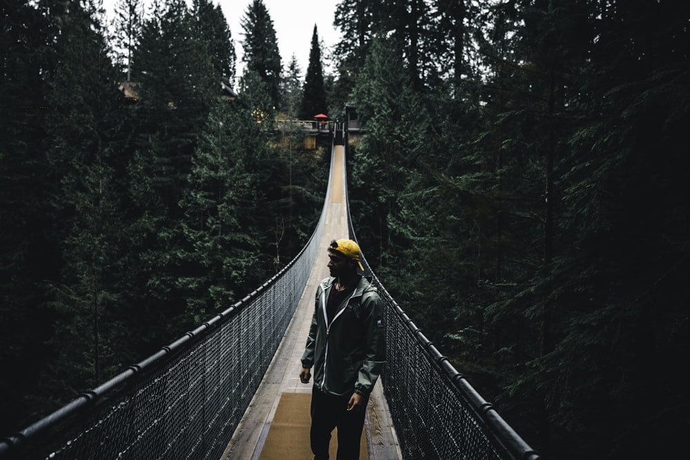 a man standing on a suspension bridge over a forest