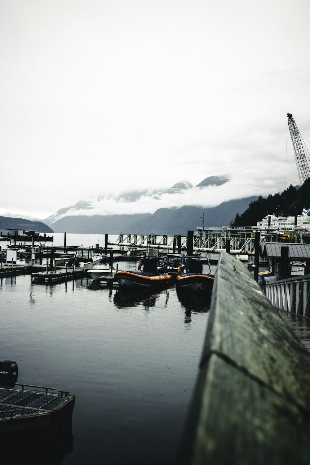 a dock with boats and a crane in the background