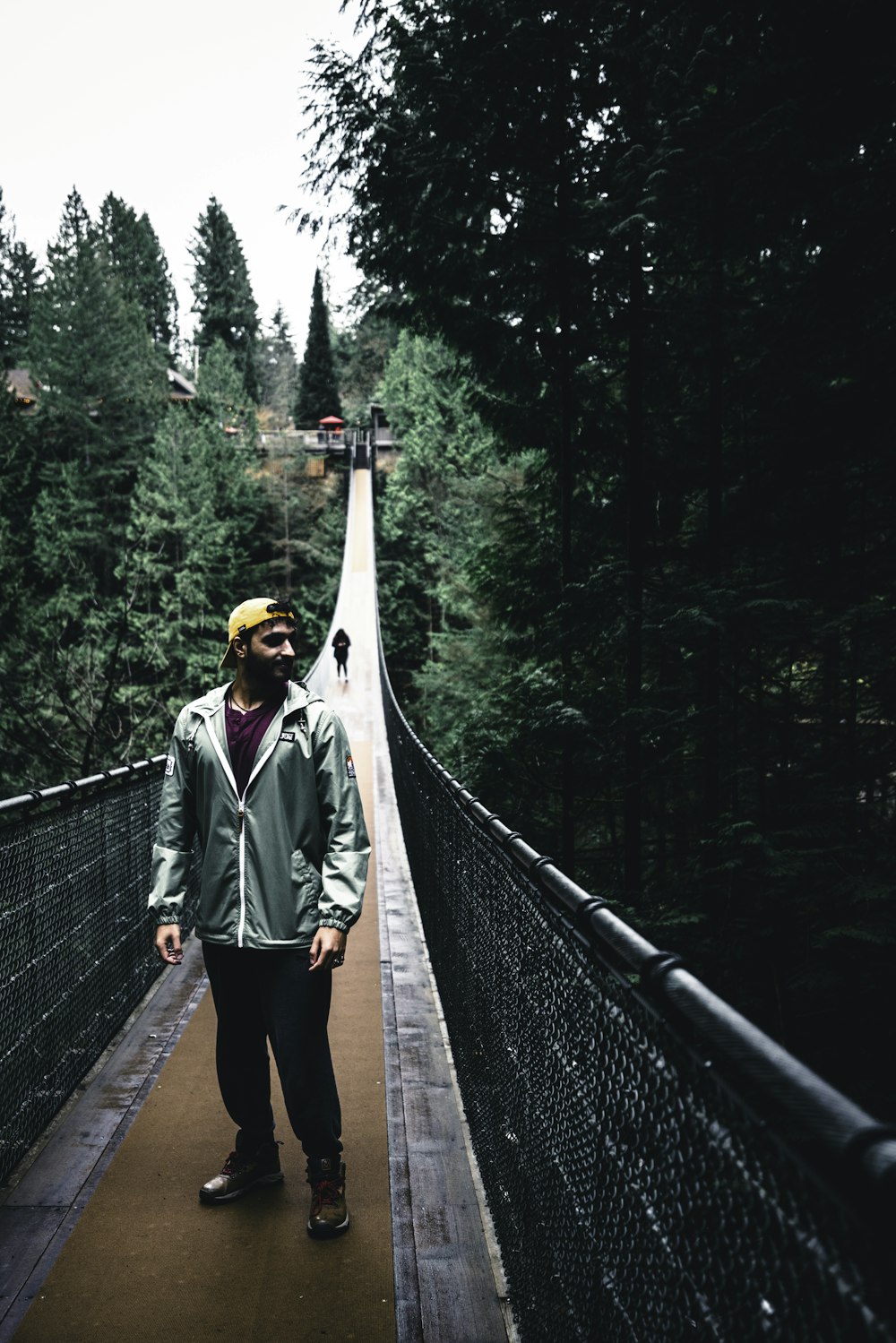 a man standing on a suspension bridge in the woods