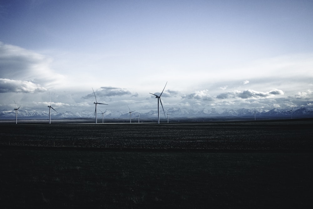 a group of windmills in a field under a cloudy sky