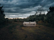 a couch sitting in the middle of a field