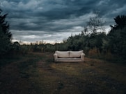 a couch sitting in the middle of a field