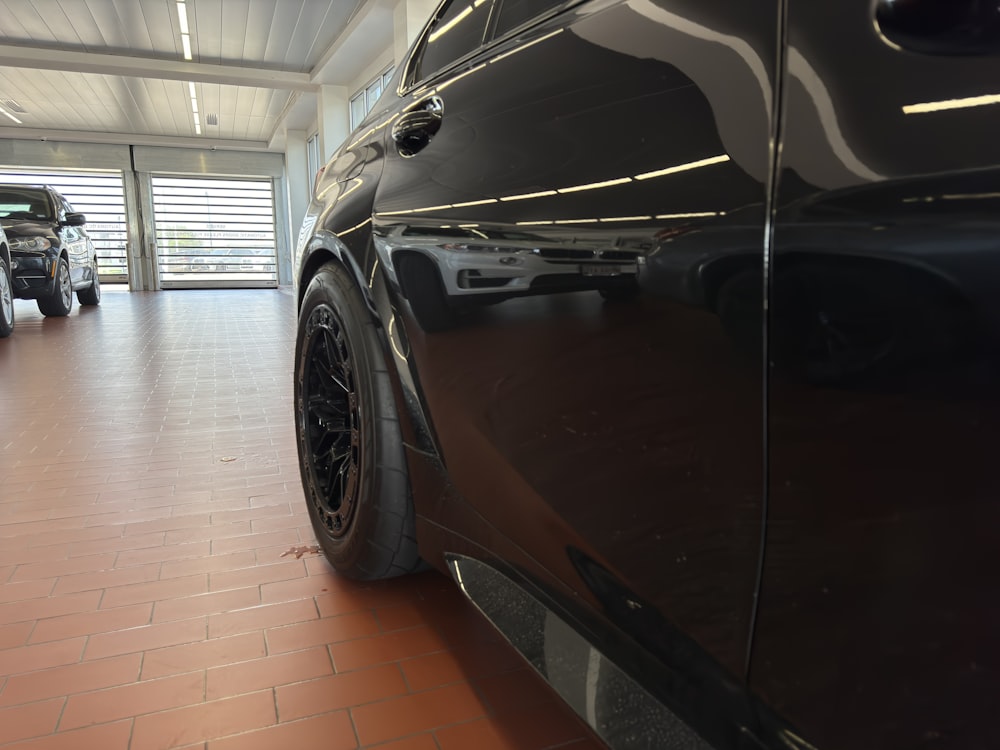 a black car parked in a garage next to another car