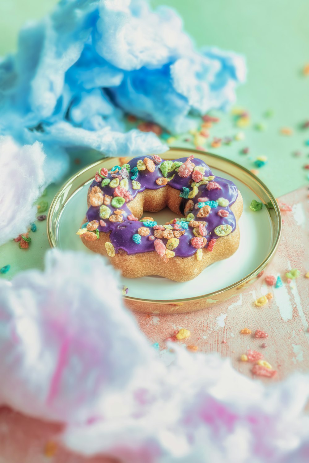 a donut with purple icing and sprinkles on a plate