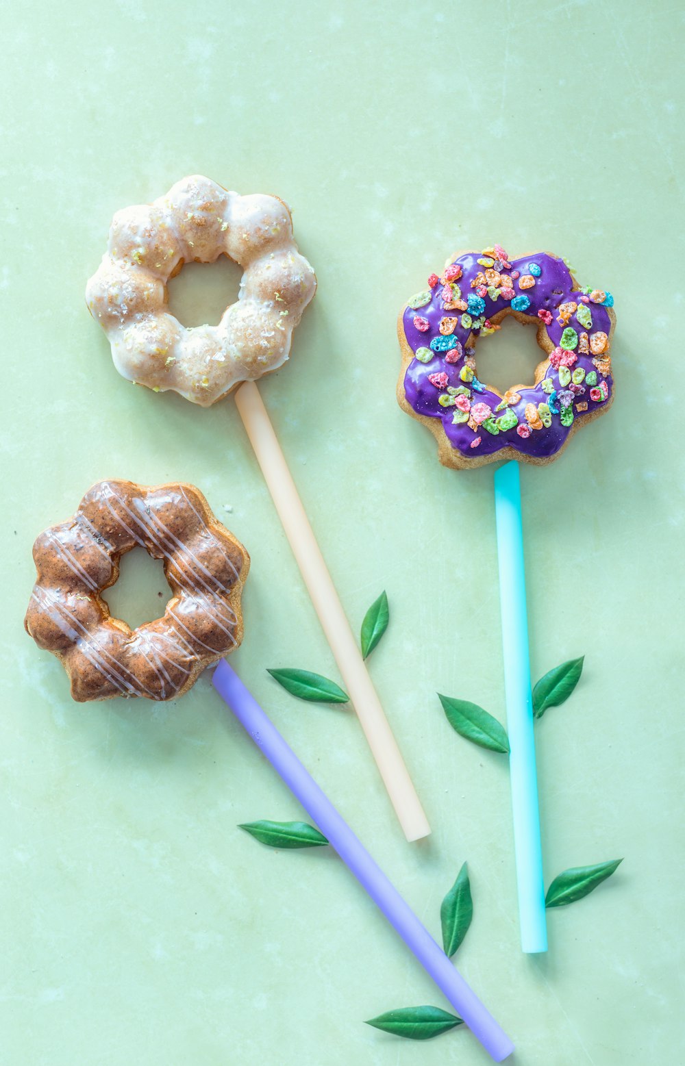 three donuts on a stick, one with sprinkles and one with