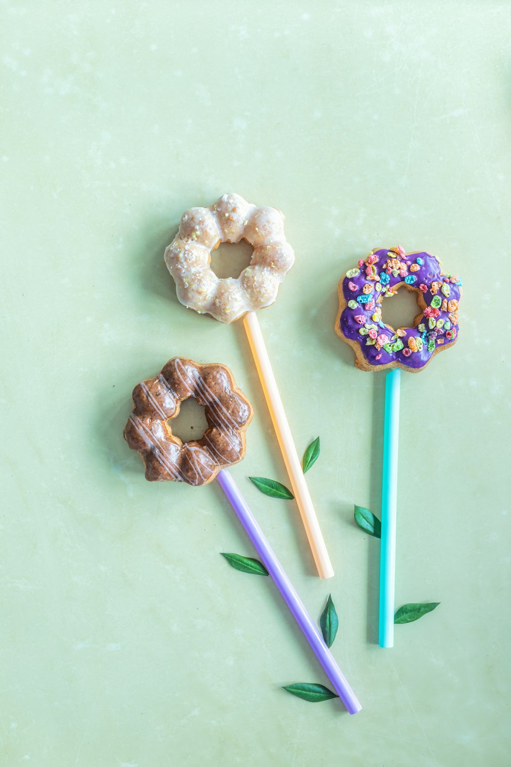 three donuts and two pencils on a green surface