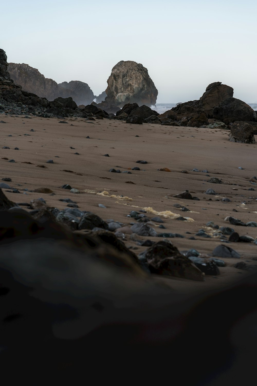 a rocky beach with a rock formation in the distance