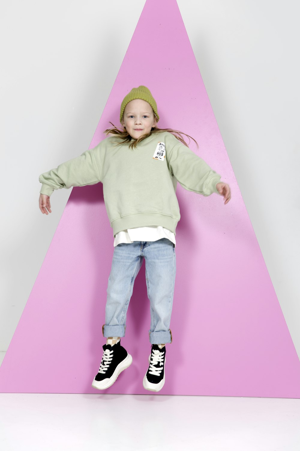 a little girl standing on top of a pink triangle