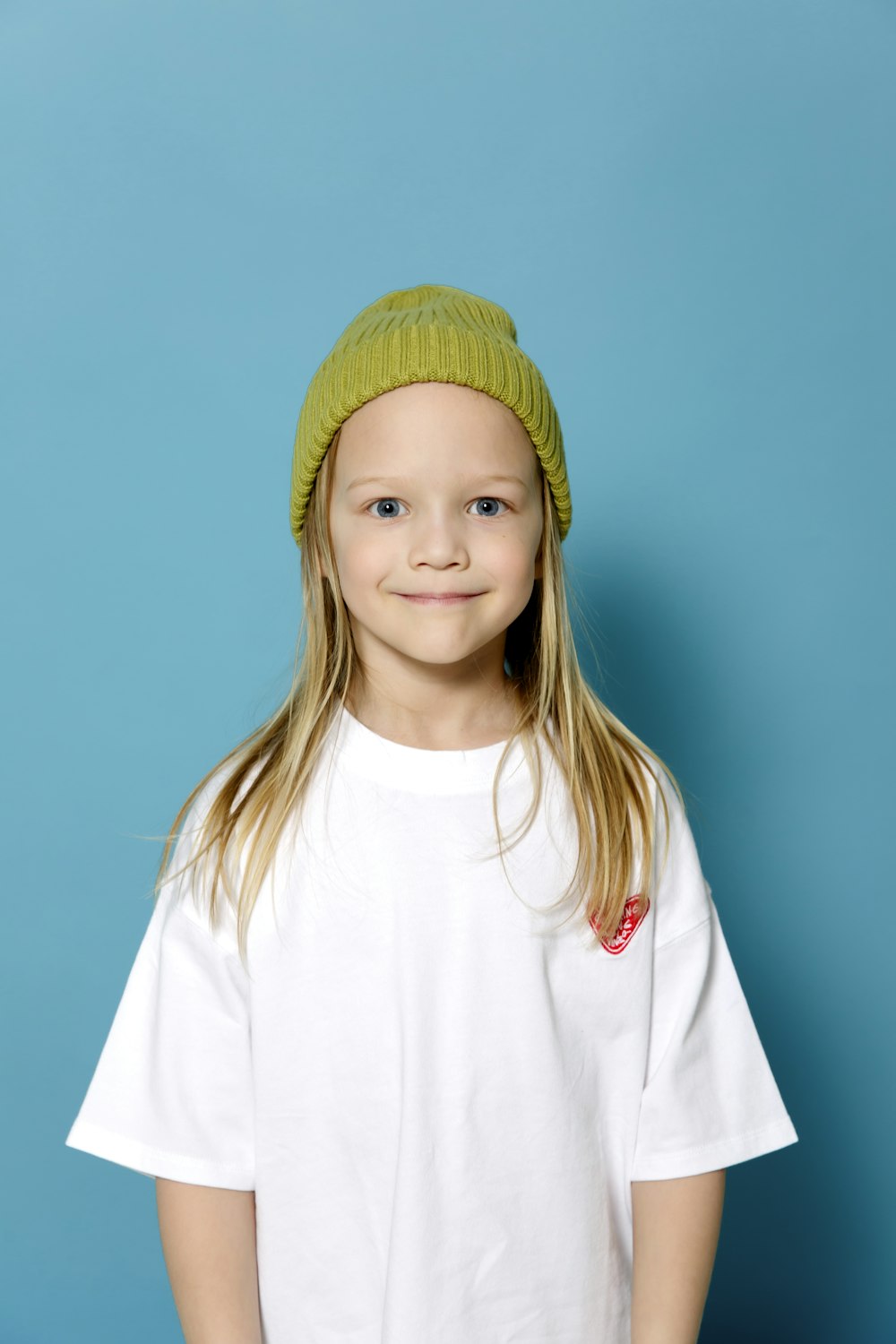 a young girl wearing a white shirt and a green hat