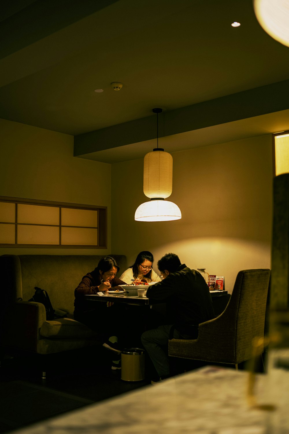 three people sitting at a table in a dimly lit room