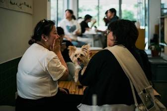 a woman sitting at a table with a small dog