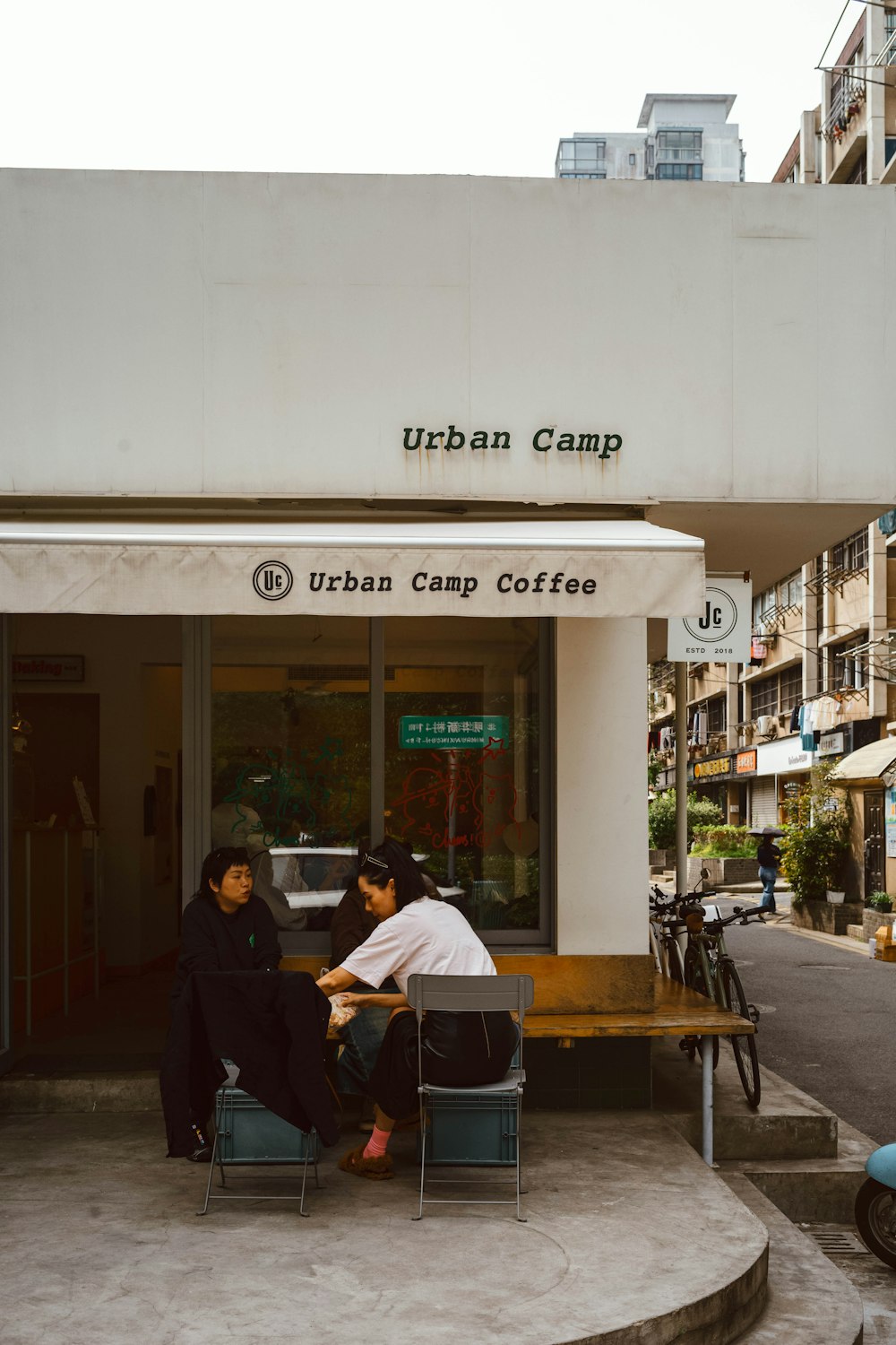 Zwei Personen sitzen an einem Tisch vor einem Café