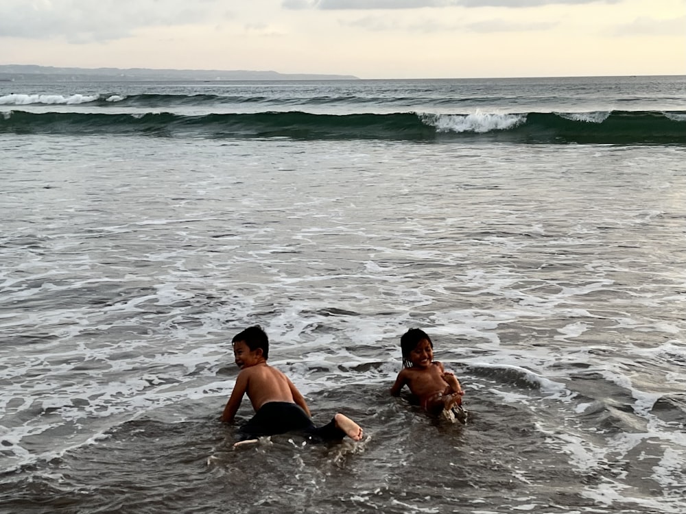 two boys playing in the water at the beach