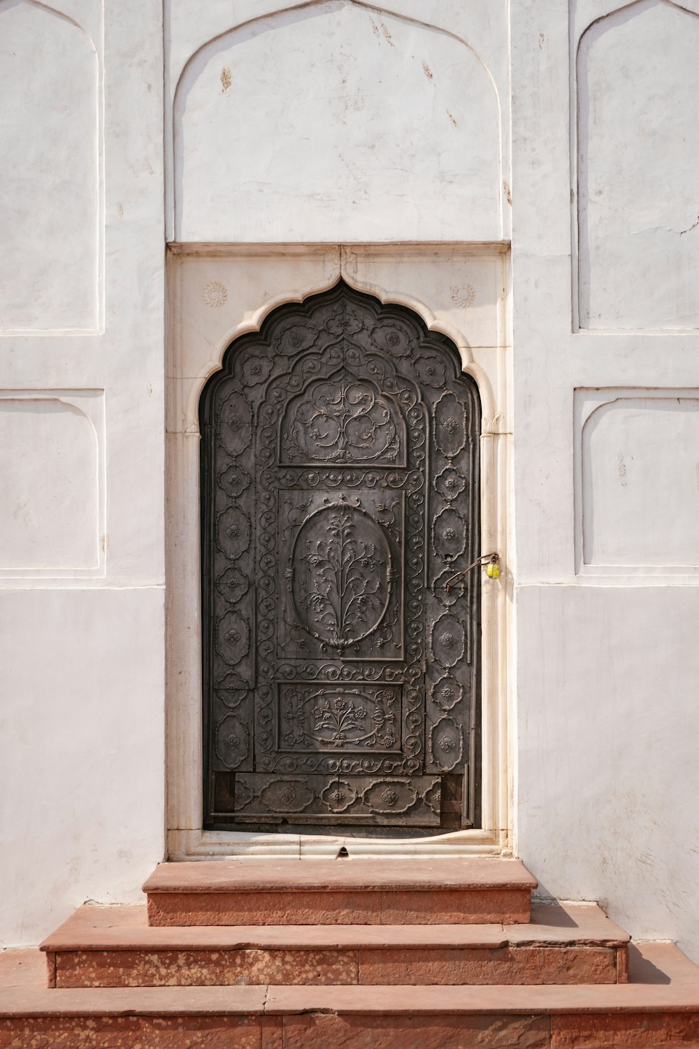 une porte dans un mur blanc avec des marches qui y mènent