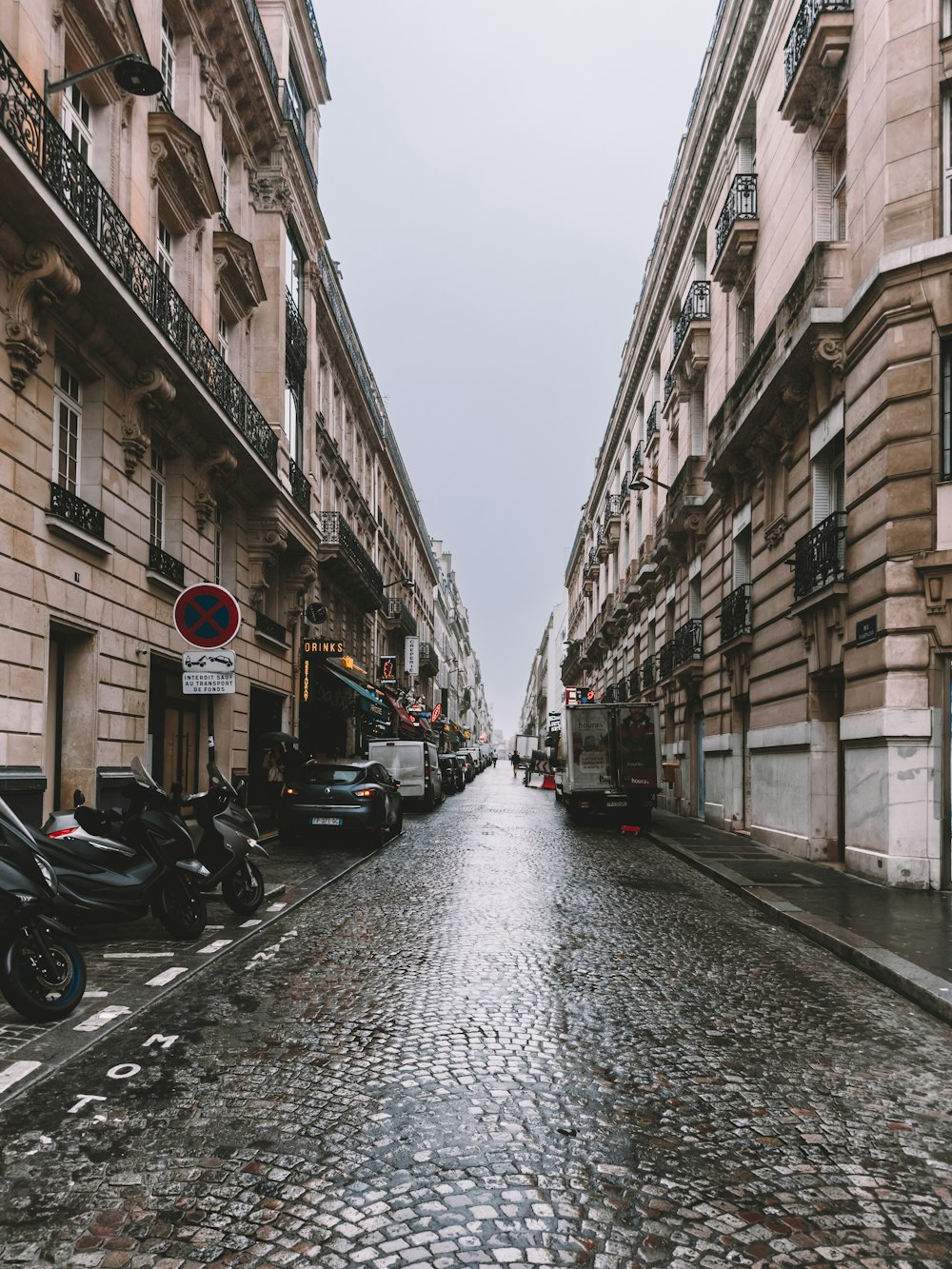 a cobblestone street lined with parked motorcycles