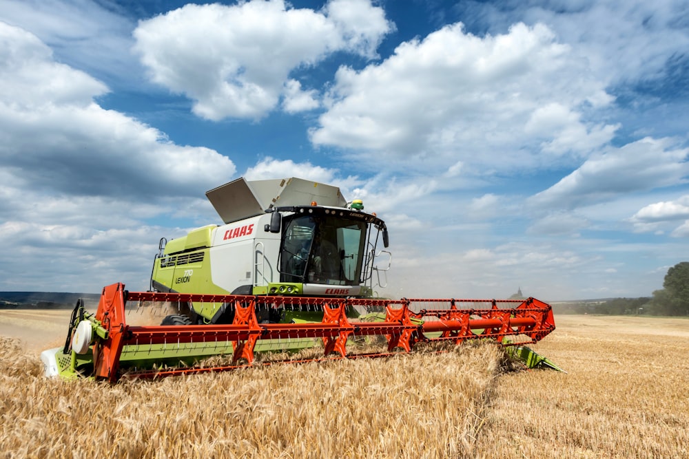 a large green and white combine in a wheat field